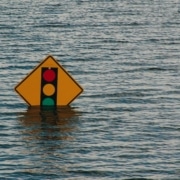 Symbolbild Klimawandel-Folgen: Ein Verkehrsschild, das eine Ampel darstellt, versinkt bei einer Überschwemmung im Wasser.